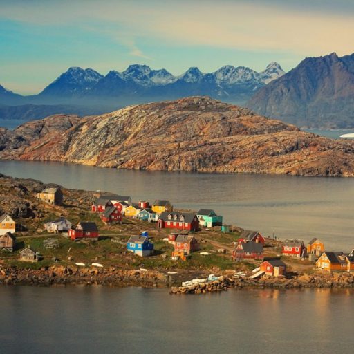 A colorful village sits on the shore of a body of water.