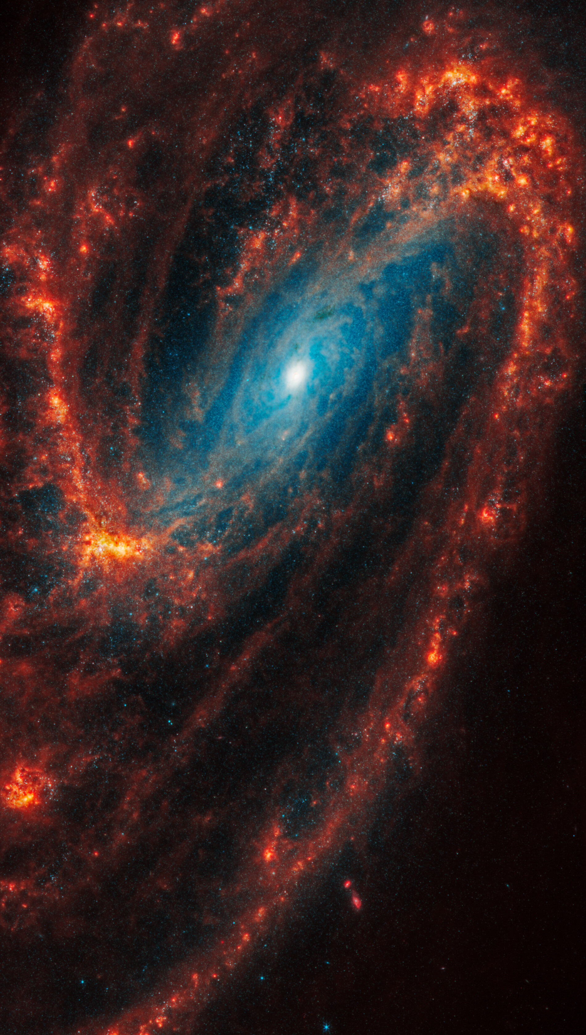 Webb&rsquo;s image of NGC 3627 shows a face-on barred spiral galaxy anchored by its central region, which has a bright blue central dot. It is surrounded by a bar structure filled with a lighter blue haze of stars, which forms a large, angled oval toward the top. Two large distinct spiral arms appear as arcs that start at the central bar. One starts at left and stretches to the top and another starts at right and extends to the bottom