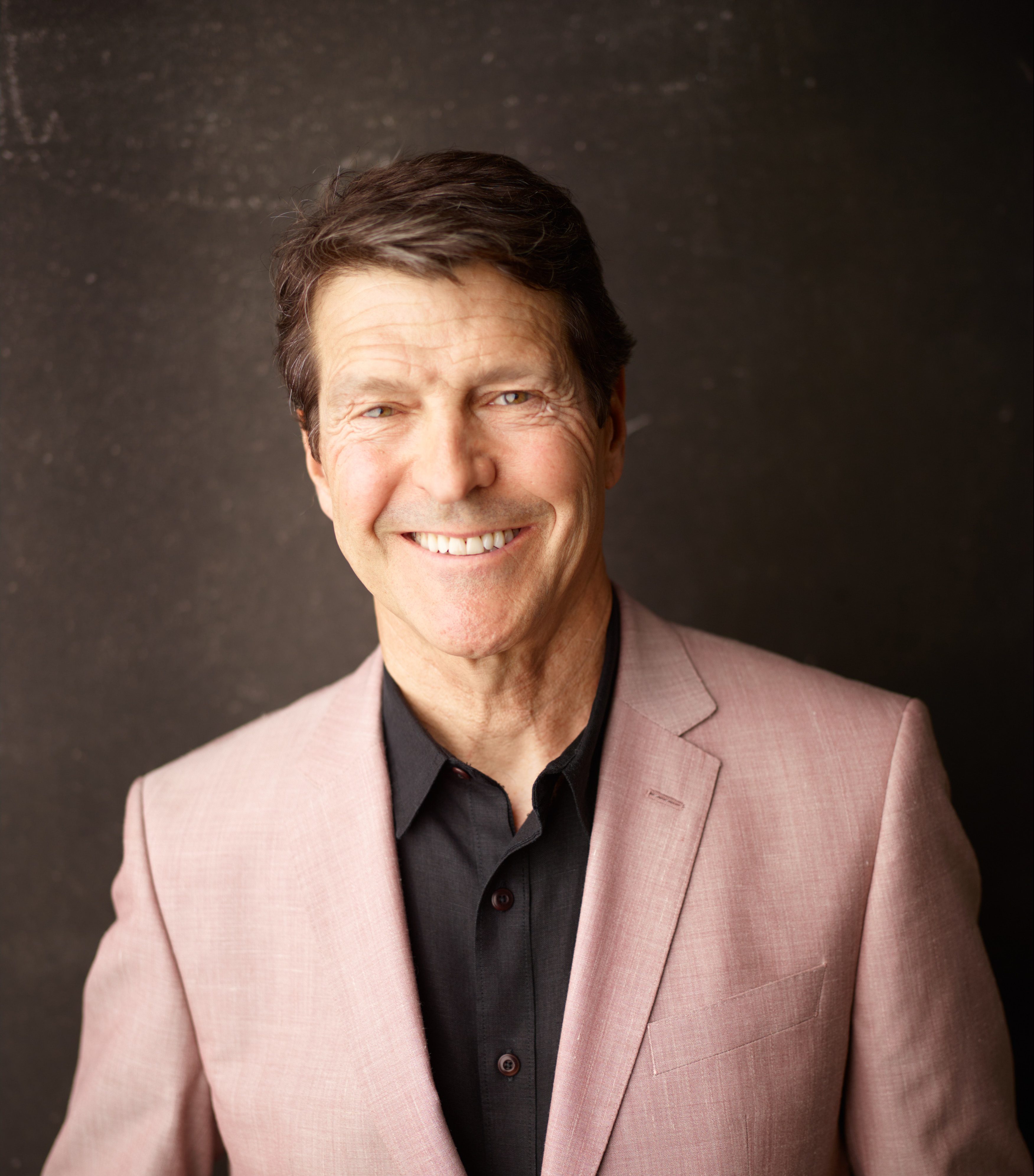 A man in a pink suit smiling for the camera.