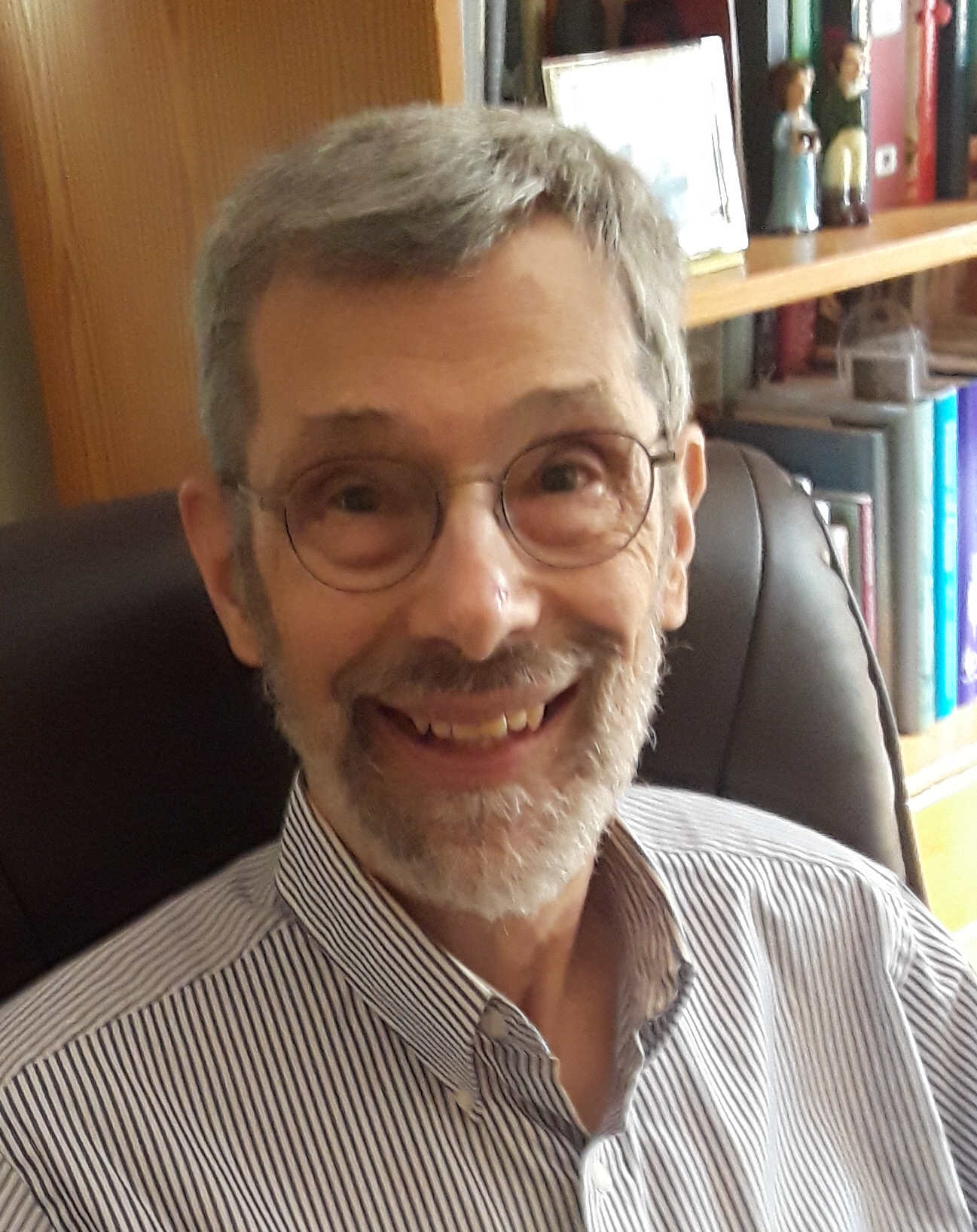 A man with glasses and a beard sitting in a chair.