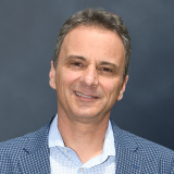 A man in a blue suit smiling for the camera.