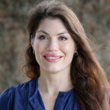A woman in a blue shirt smiles for the camera.