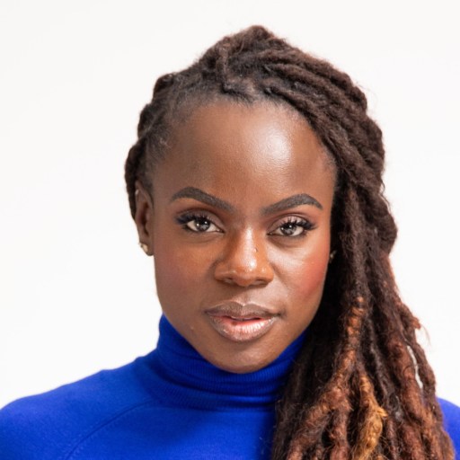 A woman with dreadlocks wearing a blue turtle neck.