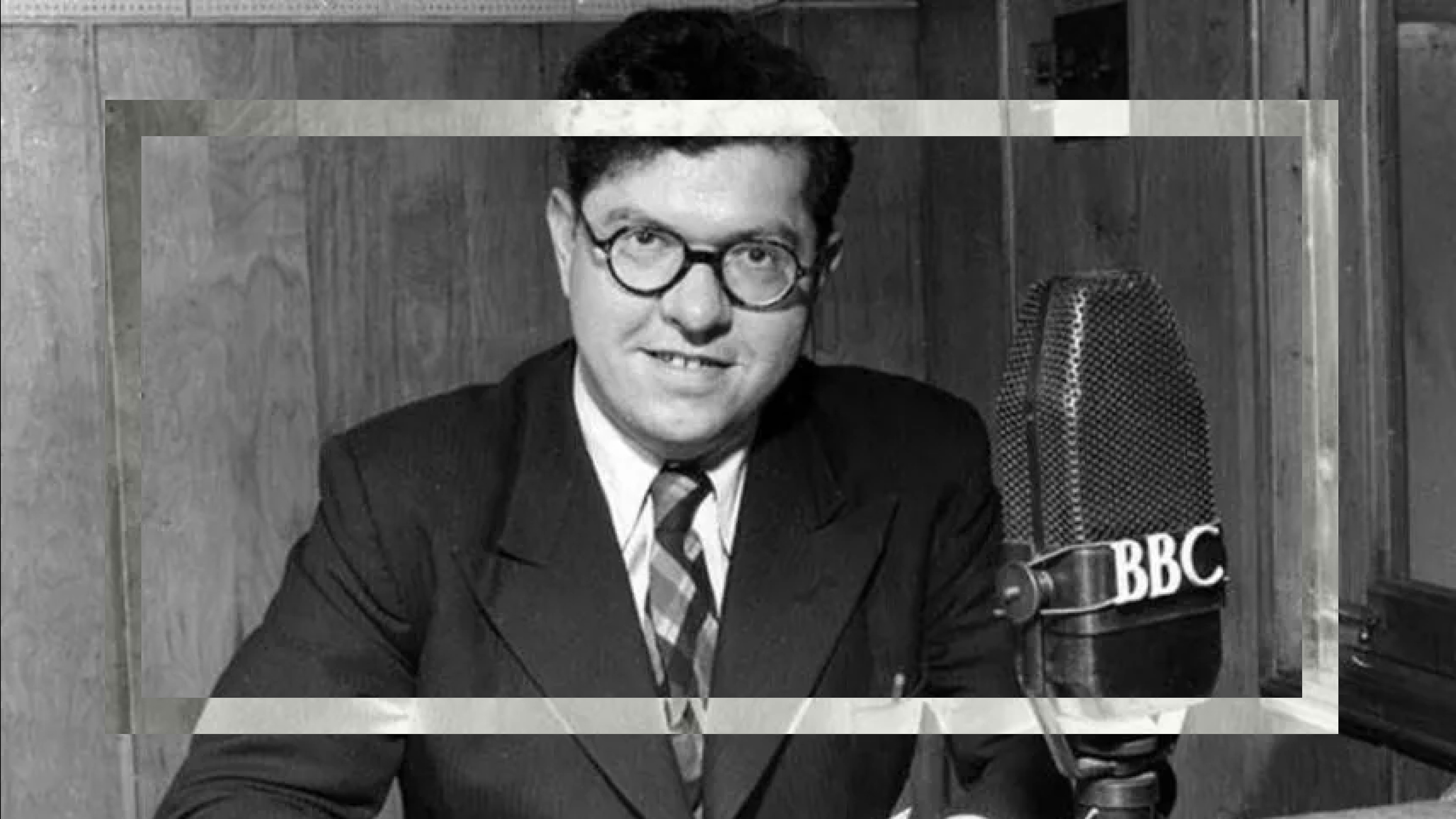 Man in a suit posing with a vintage BBC Big Bang 75 microphone.