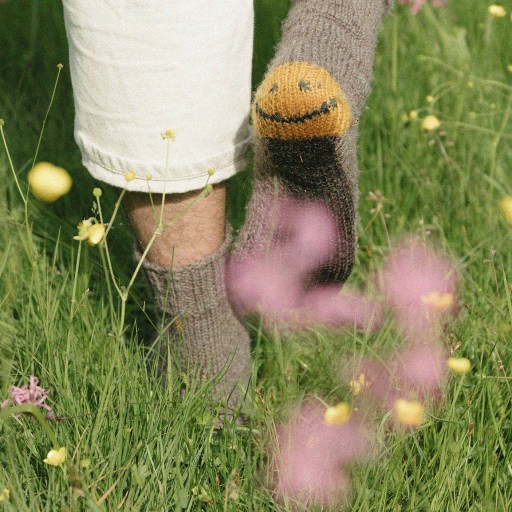 Mismatched socks on feet standing among wildflowers represent unique work-life hacks.