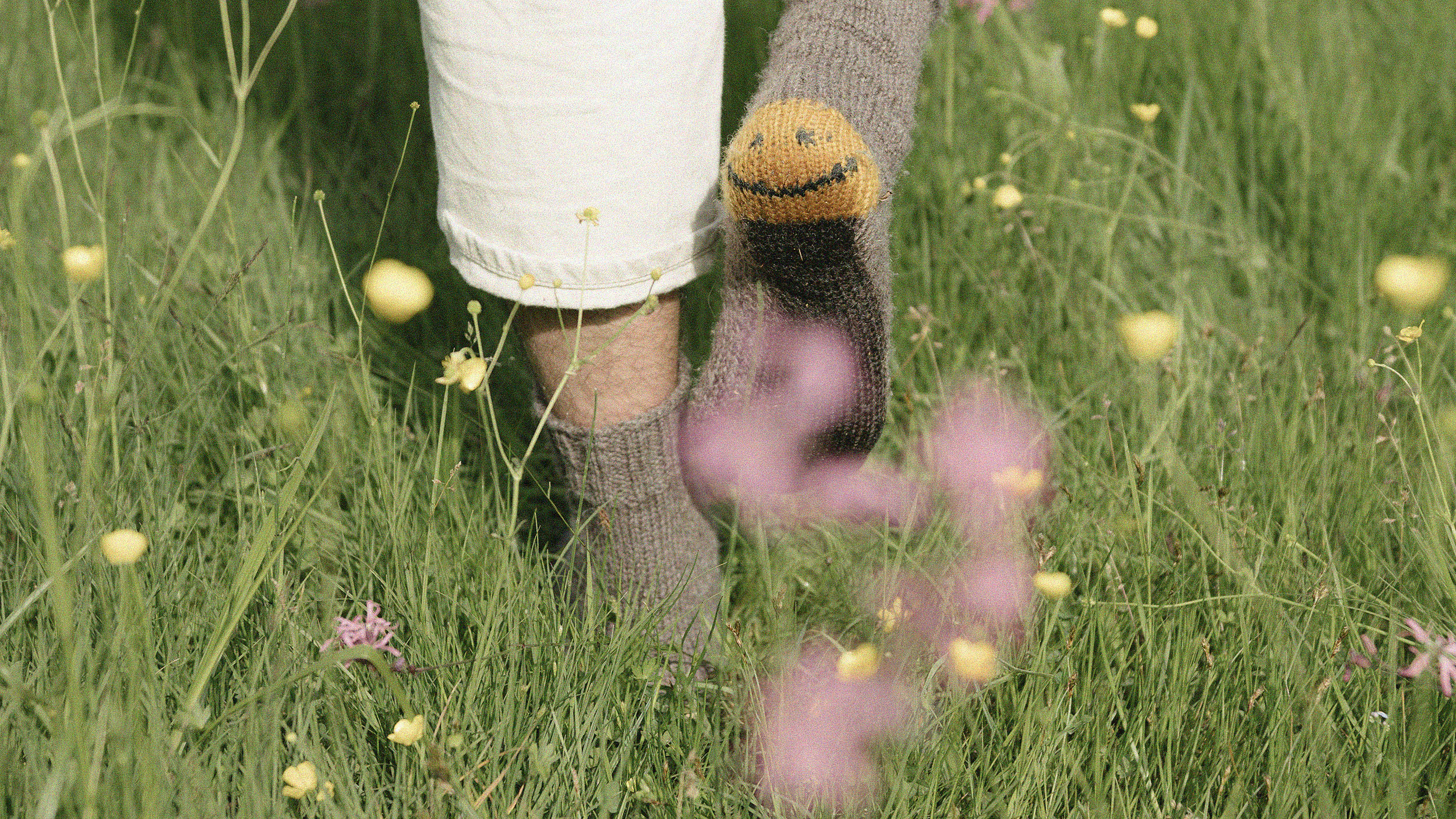 Mismatched socks on feet standing among wildflowers represent unique work-life hacks.