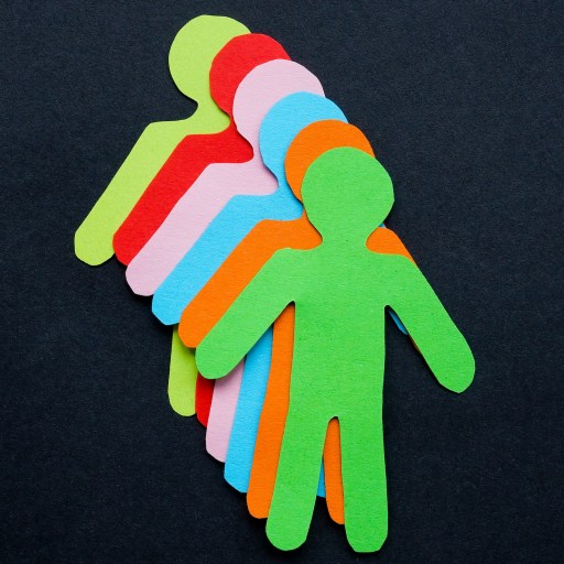 Colorful paper cutouts of human figures in a row on a black background, symbolizing love-based leadership or teamwork.