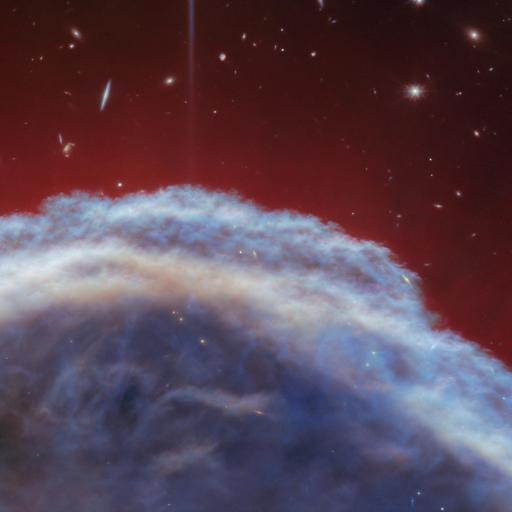 A vibrant image of the Horsehead Nebula captured by JWST, featuring a radiant blue and white glow against a deep red starry background.