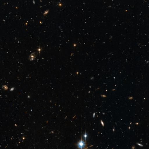 A deep space image showing numerous galaxies of different shapes and sizes scattered across a dark background, with many stars and cosmic objects, including the ancient Methuselah star, also visible throughout.