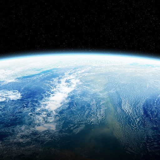 View of Earth from space showing a partially illuminated hemisphere with detailed ocean and cloud patterns against a backdrop of stars.