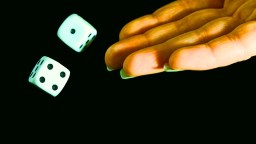 A hand is tossing two white dice with black dots against a dark background.