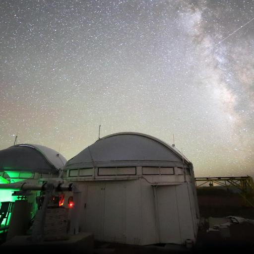 Two observatory domes under a starry night sky, with the Milky Way visible, form a stunning backdrop as an optical interferometer captures the universe's secrets.