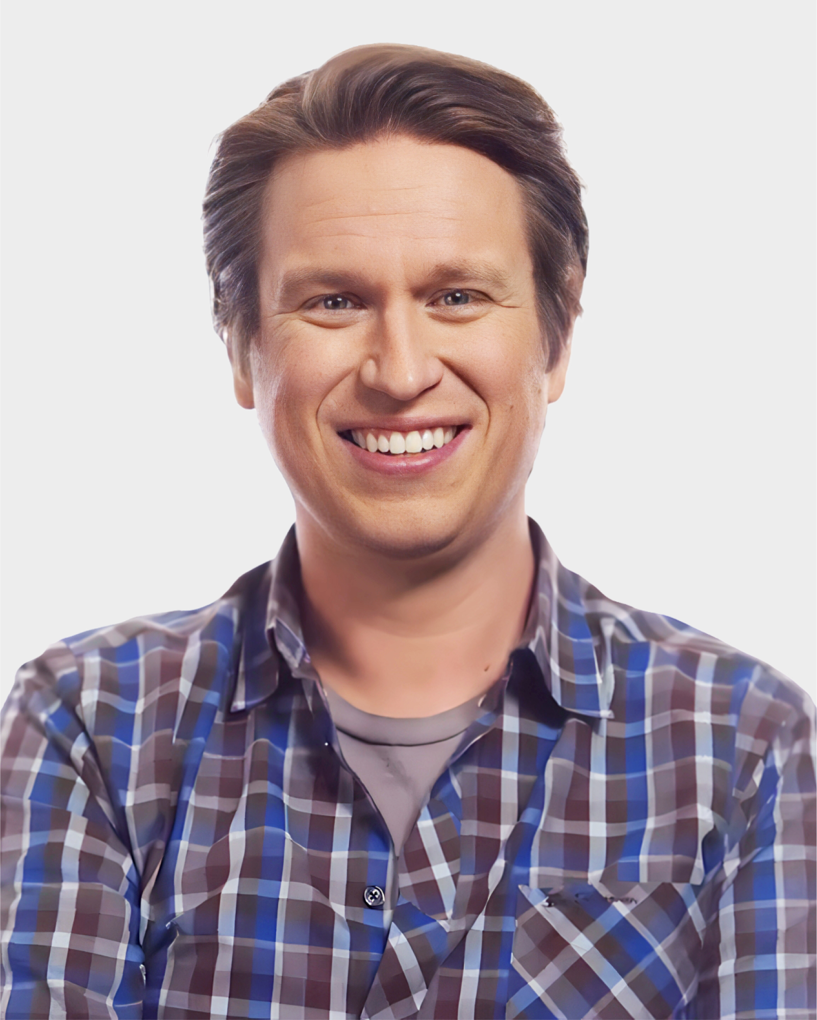 A person smiling, wearing a plaid shirt over a gray t-shirt, with arms crossed.