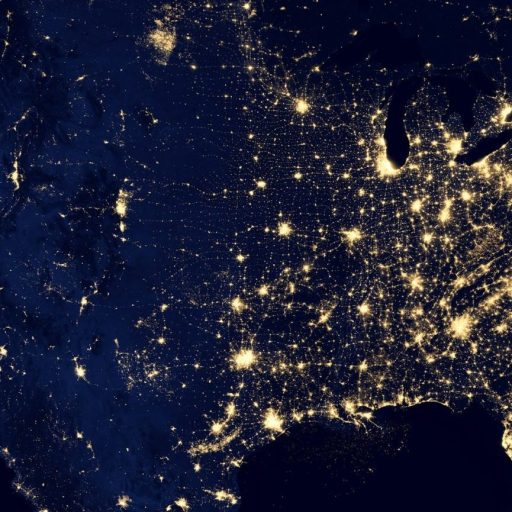 Satellite view of the United States at night reveals illuminated cities and areas, with dense clusters of lights in the eastern region, highlighting vibrant economic hubs reminiscent of workforce data concentrations, contrasted by the sparser illumination in the western regions.