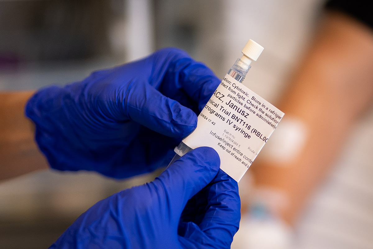 A person wearing blue gloves holds a syringe and a piece of paper, possibly preparing for a crucial lung cancer treatment.