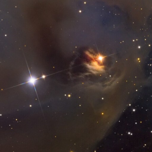 A dark nebula with dimming T Tauri stars nestled among dust and gas. The nebula casts a shadowy silhouette against a backdrop of numerous smaller stars in space.