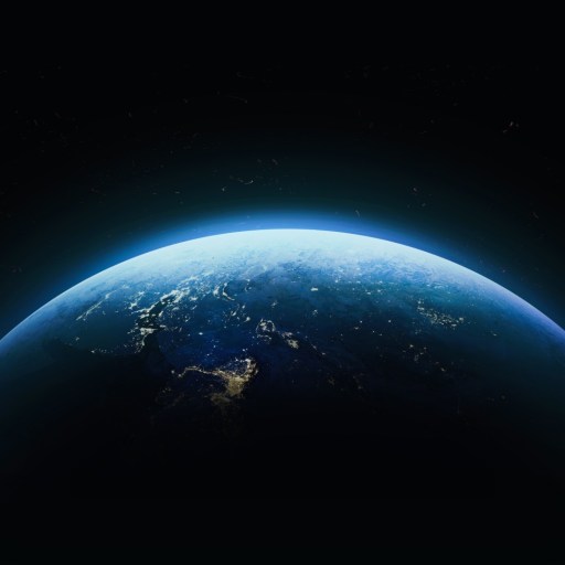 The Earth is partially illuminated against a dark space background, showing glowing city lights and a blue atmosphere.