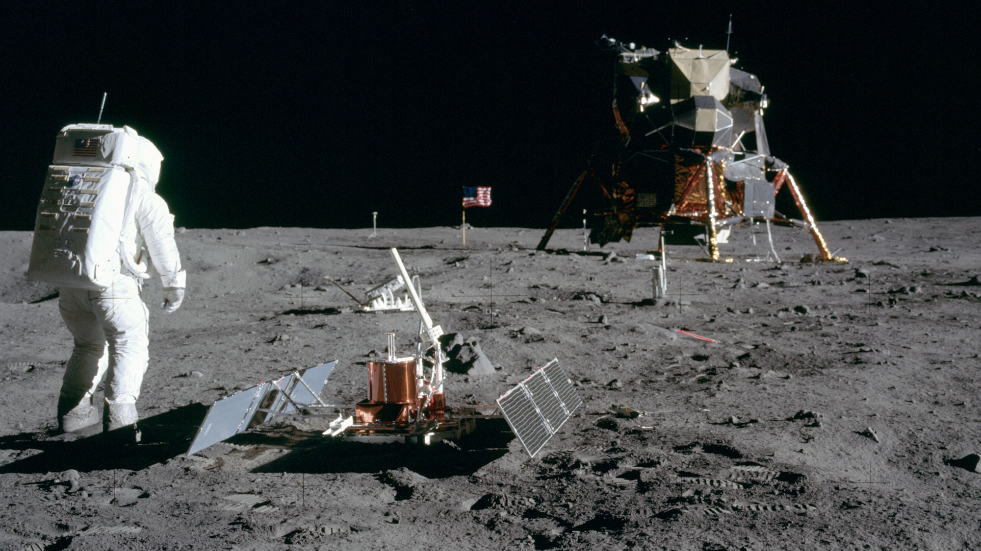 An astronaut stands proudly on the moon's surface near scientific equipment and a lunar lander, as the American flag waves in the background, symbolizing a pioneering USA nation.