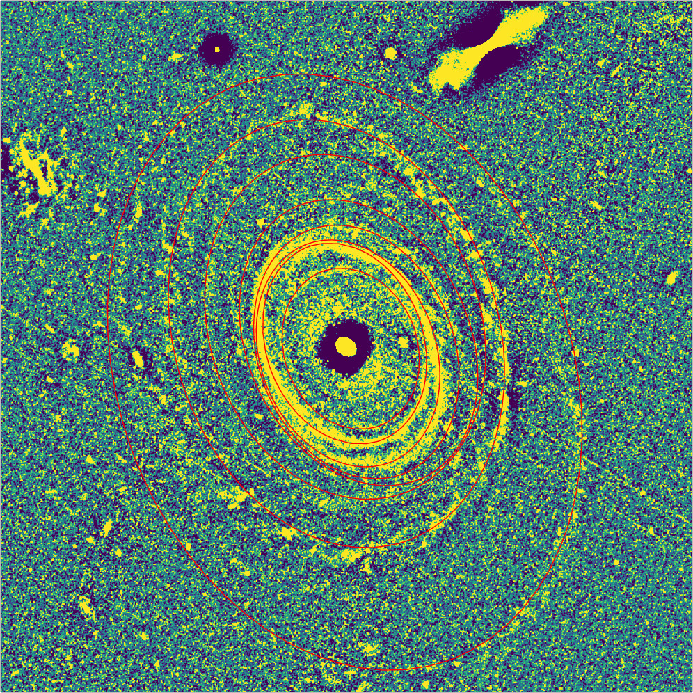 A false-color image showcases concentric, elliptical rings in yellow and orange against a green and blue speckled background, evoking the likeness of a bullseye ring galaxy or cosmic phenomenon.