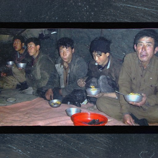 Five men, immersed in conversation, sit indoors on a blanket, eating from metal bowls. Despite the cloud of ignorance surrounding them about modern science, they share stories and laughter as a red bowl rests prominently at their center.