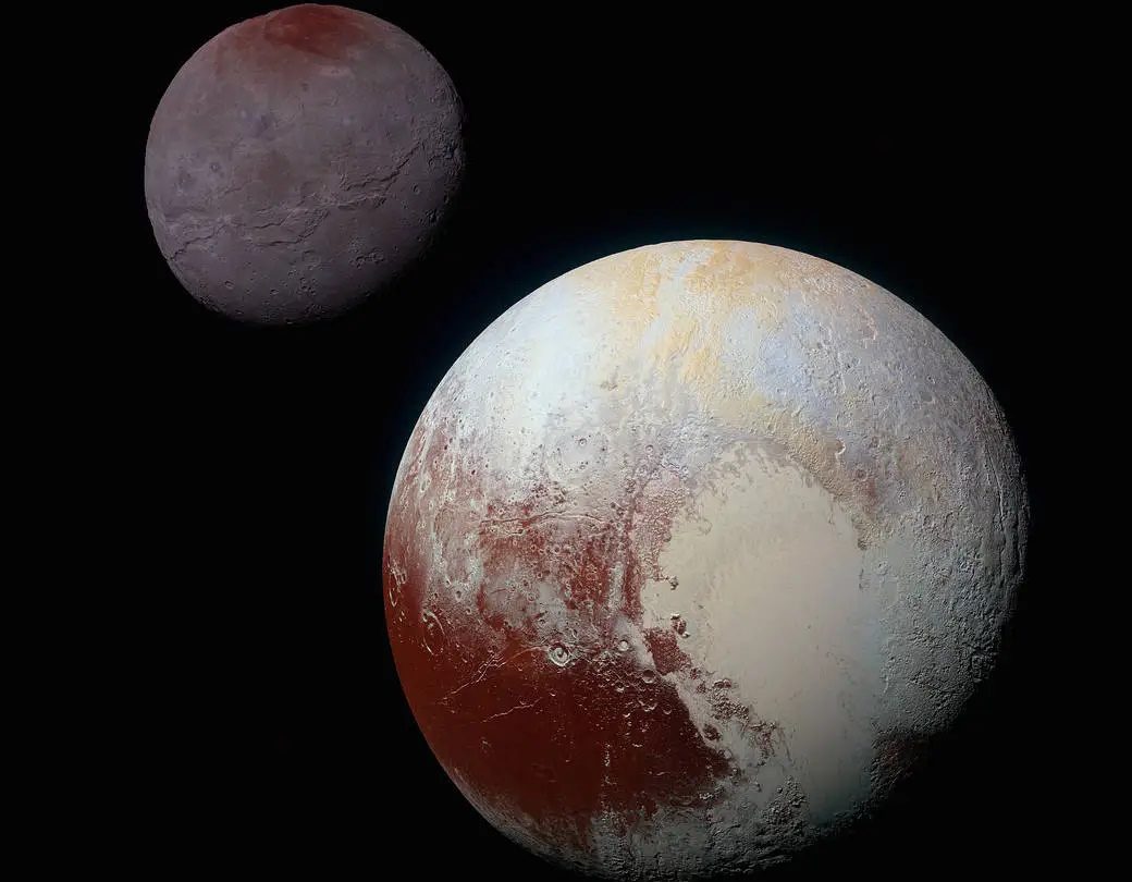 Image of Pluto and its moon Charon in space. Pluto shows distinct surface features with areas of varying colors, while Charon appears smaller with a darker, smoother surface.