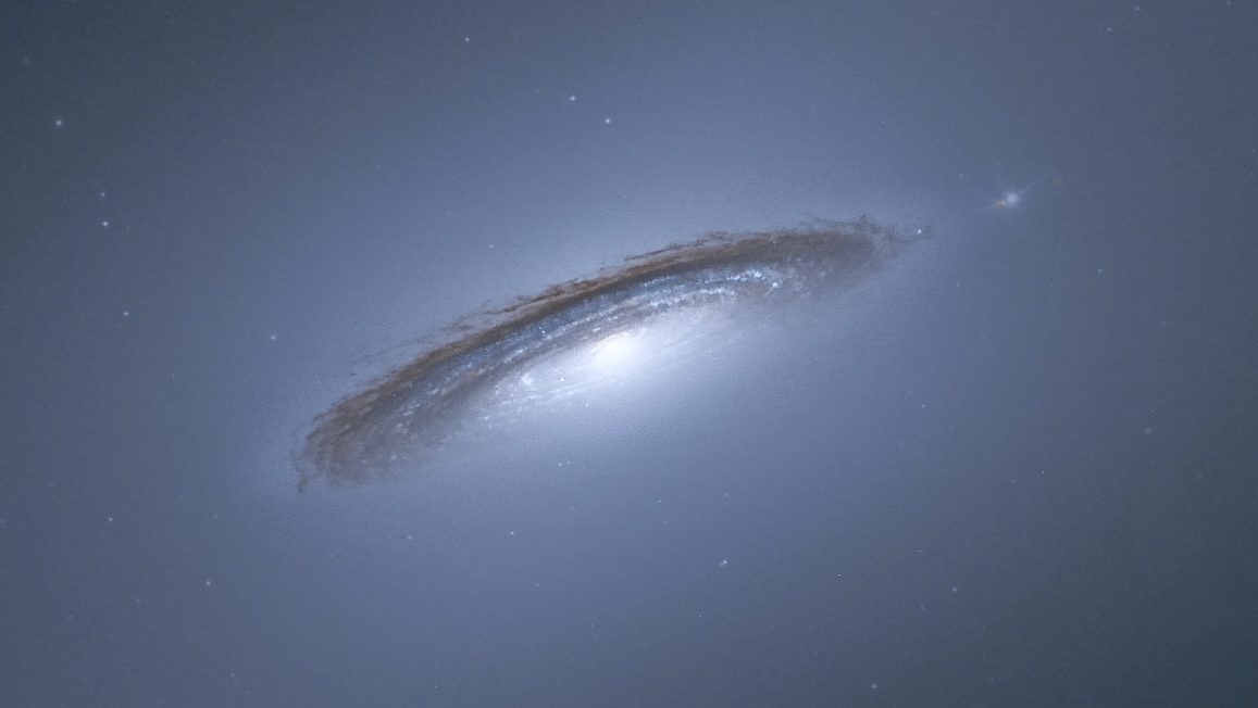 A tilted spiral galaxy gracefully tipped towards the viewer reveals a bright core and dark, dusty rings, set against the infinity of deep blue space.
