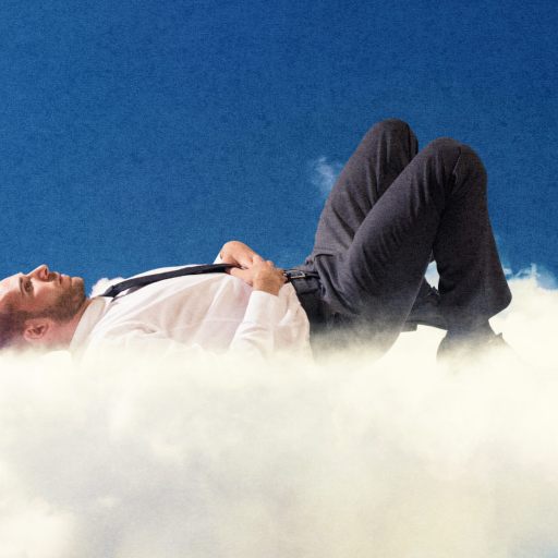 A man in business attire lies relaxed on a cloud against a clear blue sky, embodying inner stillness.
