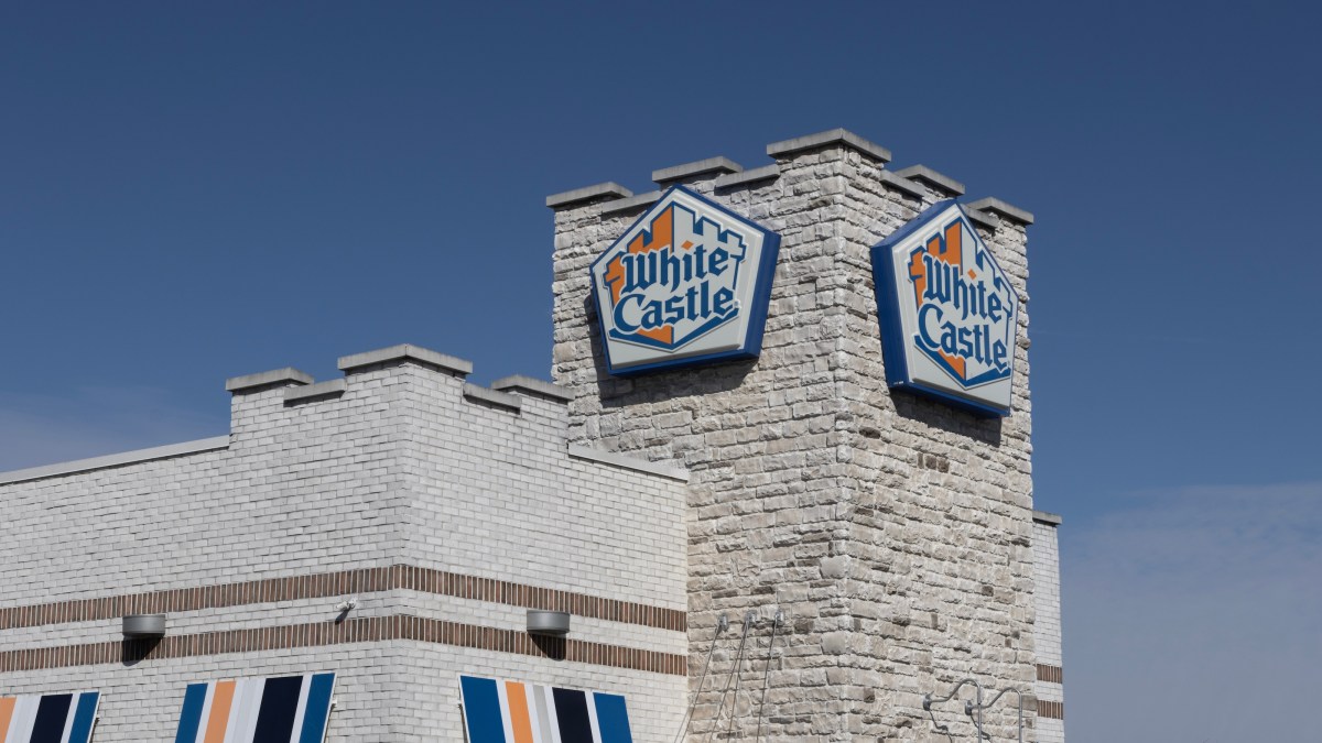 White Castle restaurant building with logo signs on a stone tower stands proudly against a clear blue sky, embodying an evergreen business model that continues to thrive.