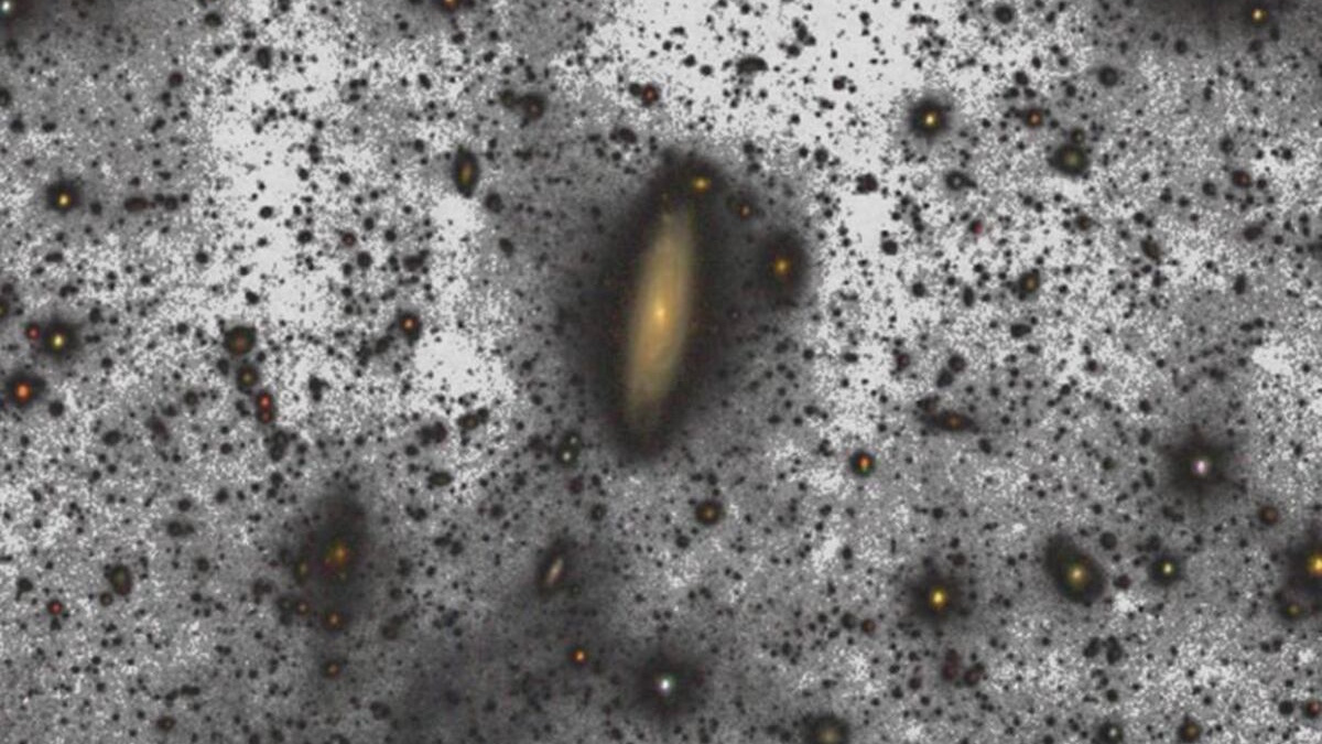 The spiral galaxy, surrounded by dim stars and interstellar dust, stands out against a dark background, shining brighter than astronomers once imagined.