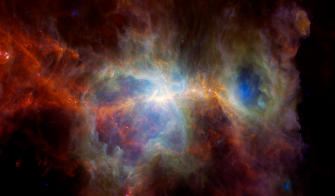 A colorful nebula with glowing clouds of gas and dust in shades of red, orange, yellow, blue, and green against a dark space background.