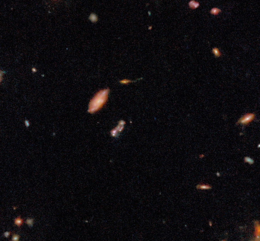 A view of deep space showing numerous distant galaxies of various shapes and sizes against a black background.