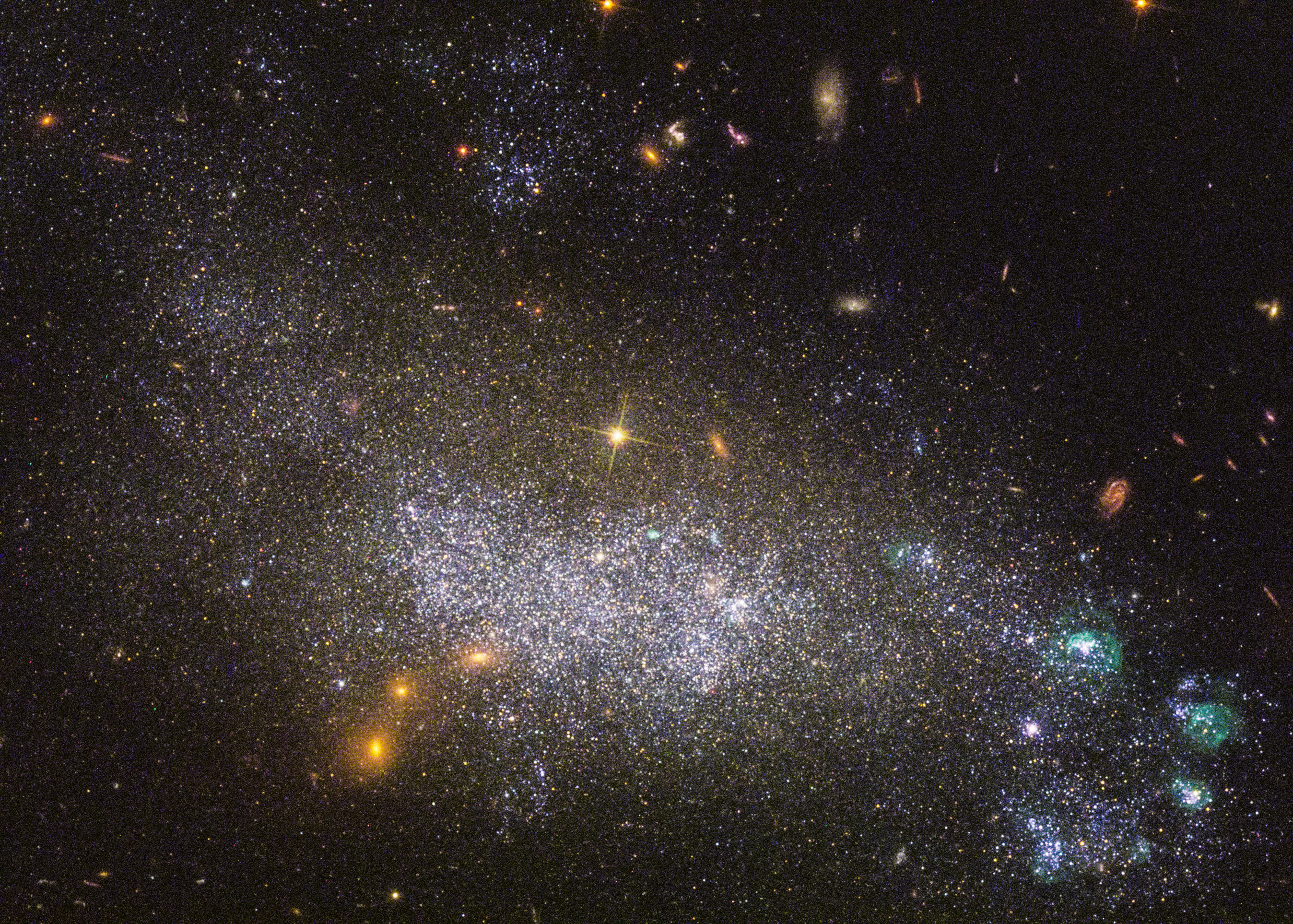 A dense star field in deep space features countless bright stars, glowing clusters, and distant galaxies set against a black background&mdash;reminding us how vast space can sometimes deceive the eye with its mysterious appearance.