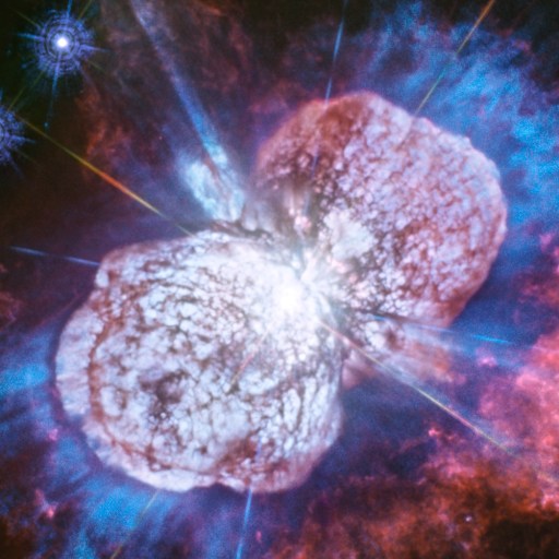 Two bright, irregularly shaped nebula clouds with blue, purple, and pink gases dominate the dark space background, where dazzling stars twinkle—reminding us that in space, appearances can deceive.