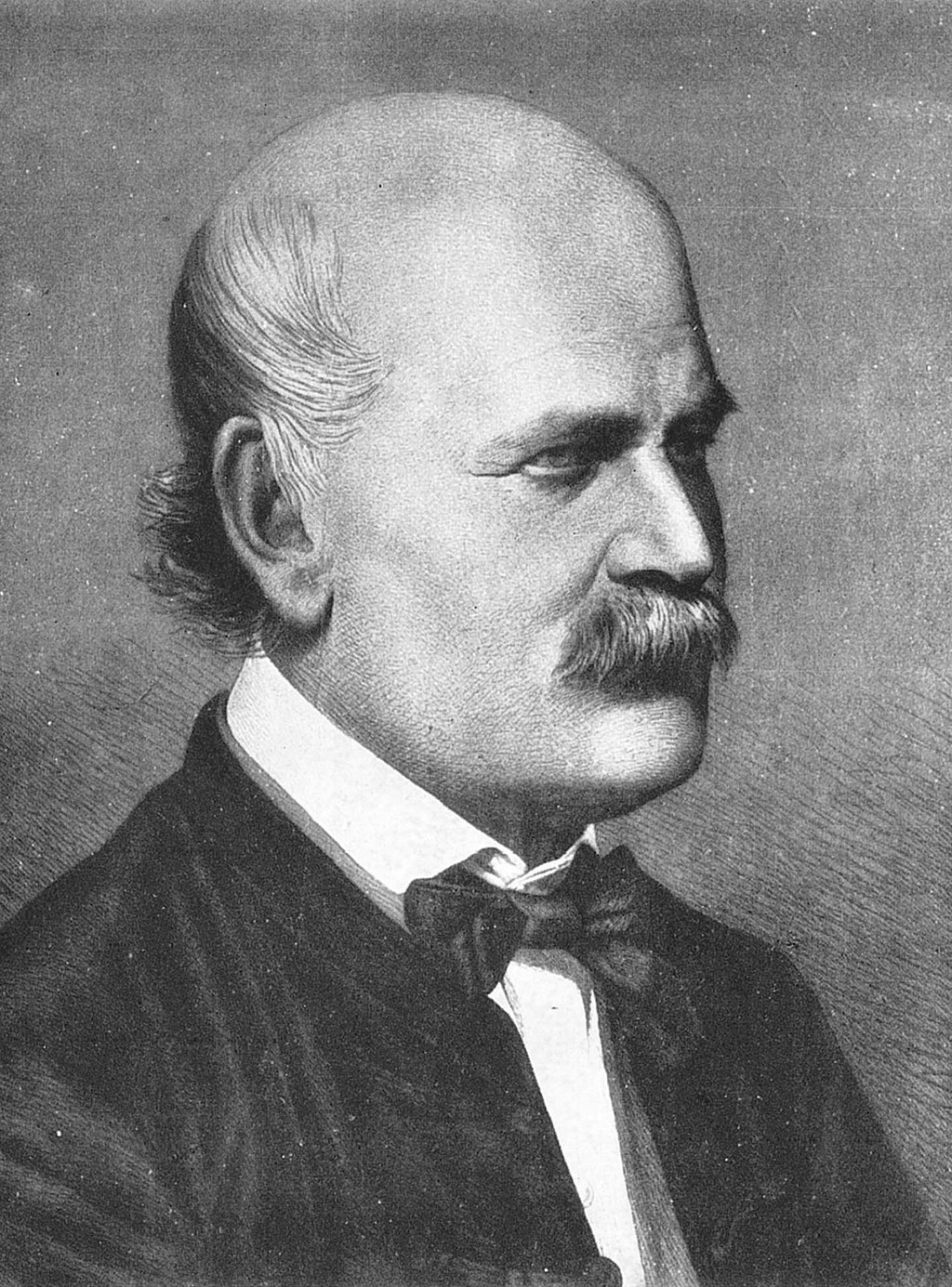 Black and white portrait of a bald man with a mustache, wearing a suit, white shirt, and bow tie, facing toward the right.