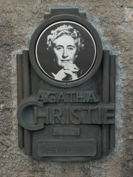 A metal plaque with a portrait of Agatha Christie and text reading &ldquo;Agatha Christie Mile, Torre Abbey.&rdquo;.