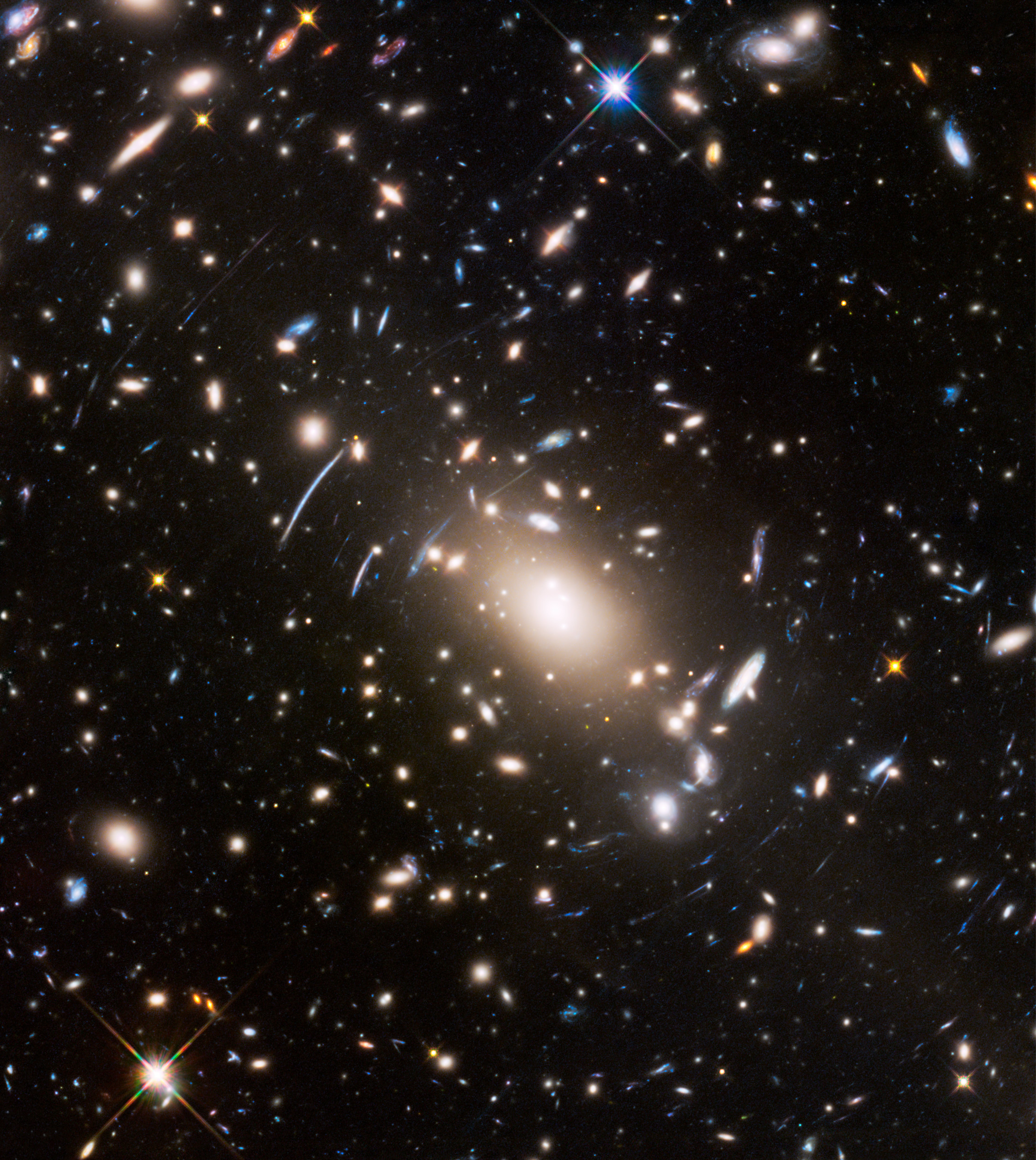 A dense galaxy cluster with numerous bright stars and elongated arcs caused by the JWST&rsquo;s most extreme gravitational lens, set against a dark background in deep space.