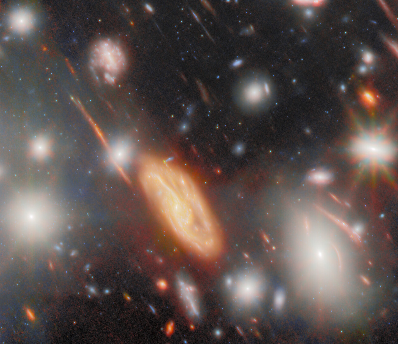 Image of a deep space region captured by JWST shows numerous galaxies and bright stars, with a prominent yellow spiral galaxy at the center&mdash;its appearance shaped by the most extreme gravitational lens effects among vibrant celestial objects.