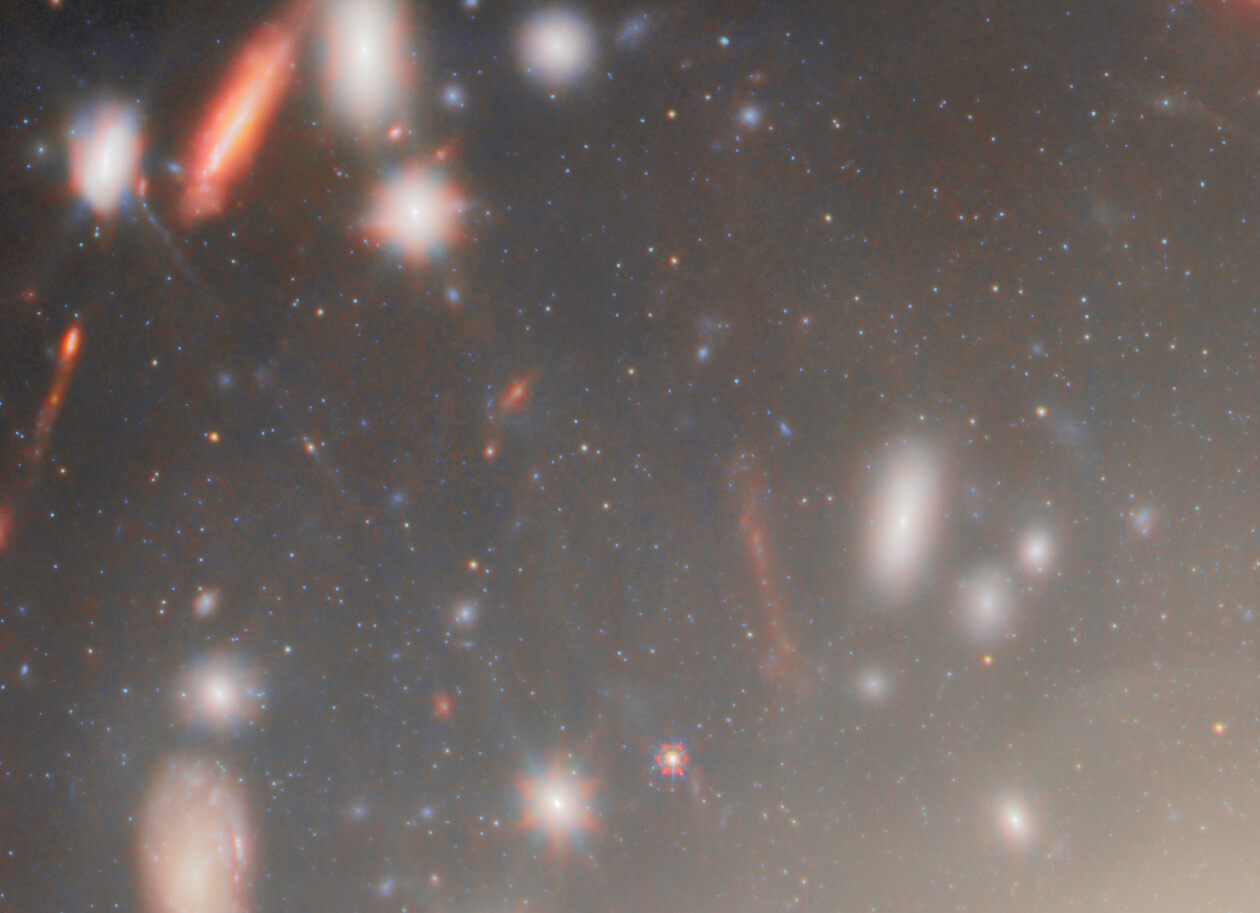 A field of distant galaxies and stars, captured by JWST, showcases some objects blurred by motion or distance&mdash;revealing the most extreme gravitational lens in the cosmos against a dark background.