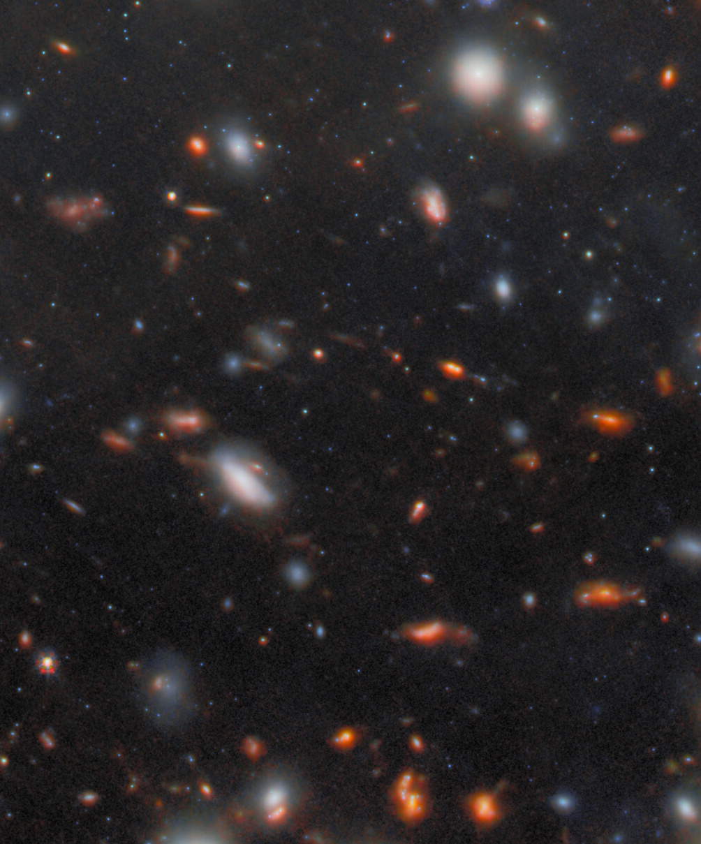A field of distant galaxies, revealed by JWST&rsquo;s most extreme gravitational lens, showcases varying sizes and colors scattered across a dark space background, with numerous points of light and diffuse glows.
