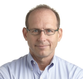 A middle-aged man with short hair, glasses, and a light blue collared shirt looks directly at the camera against a plain white background.