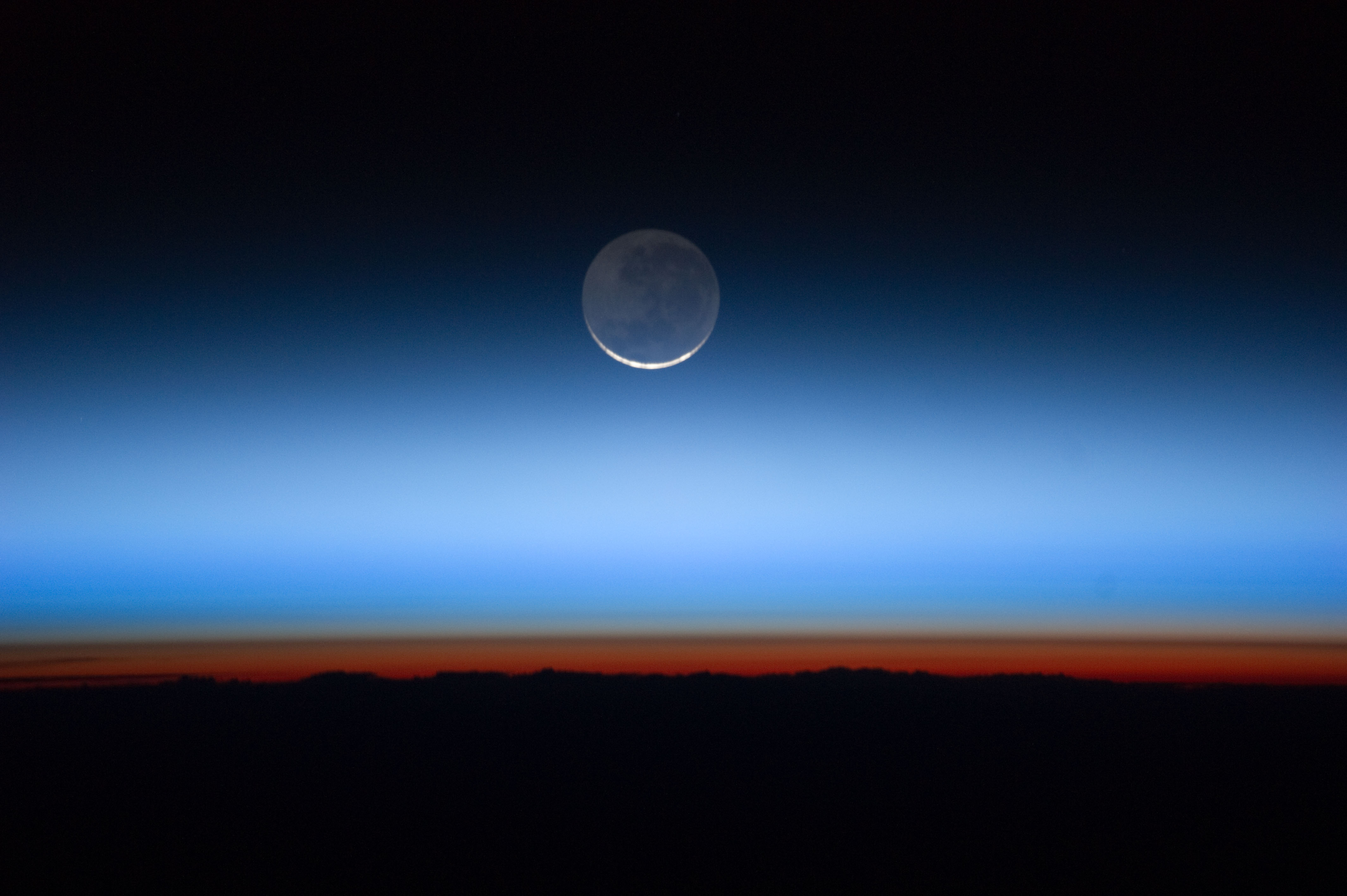 A crescent moon is visible above the horizon with a gradient sky transitioning from dark blue to orange&mdash;perfect for inspiring 5 science lessons about the moon at sunrise or sunset.