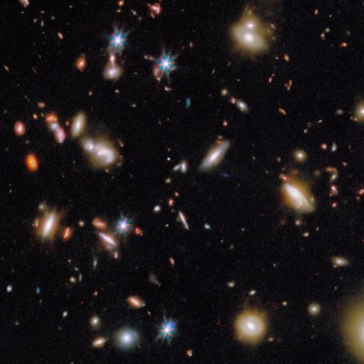A dense field of distant galaxies and bright stars against a black background, as captured in a JWST early galaxies deep space telescope image.