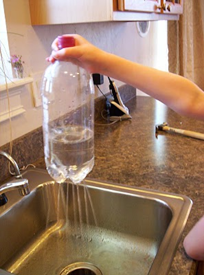A hand holds a plastic bottle filled with water over a sink, with water streaming out of holes in the bottom&mdash;demonstrating how even scientists explore the possibility behind simple phenomena.