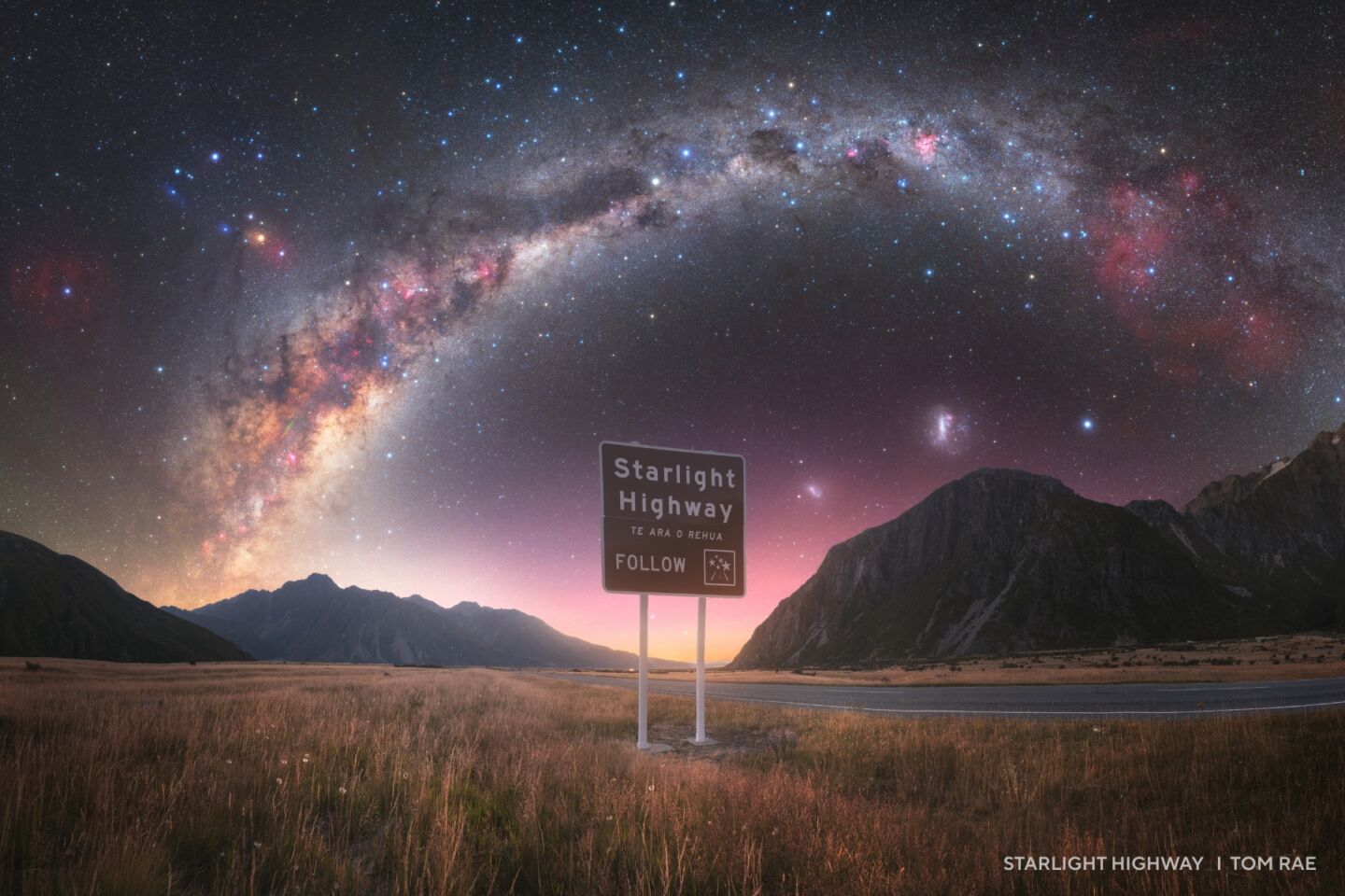 A road sign labeled "Starlight Highway" stands in a grassy plain with mountains in the background and a vivid Milky Way, capturing the magic found in 2025 night sky images.