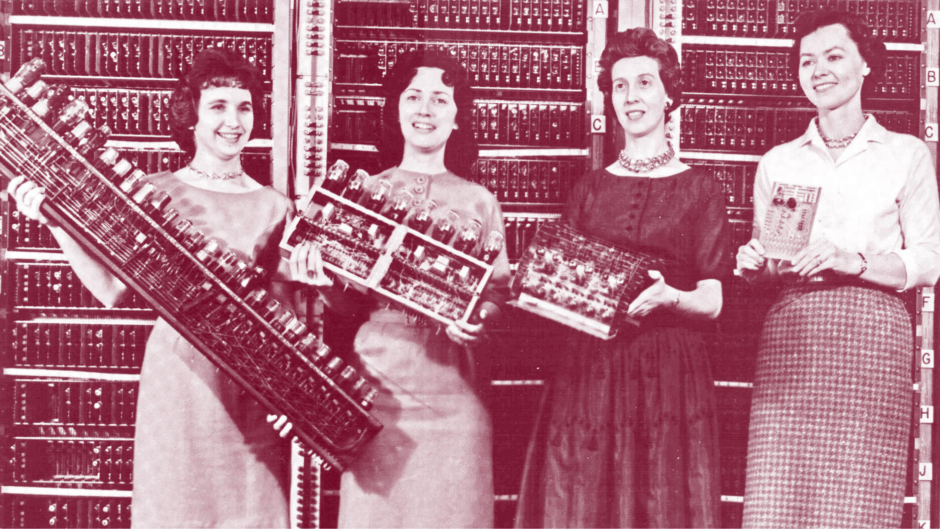 Four women stand in front of a vintage computer, each holding different components of its hardware, with the computer's panel visible in the background—an image reminiscent of historical innovation studied by Angus Fletcher.