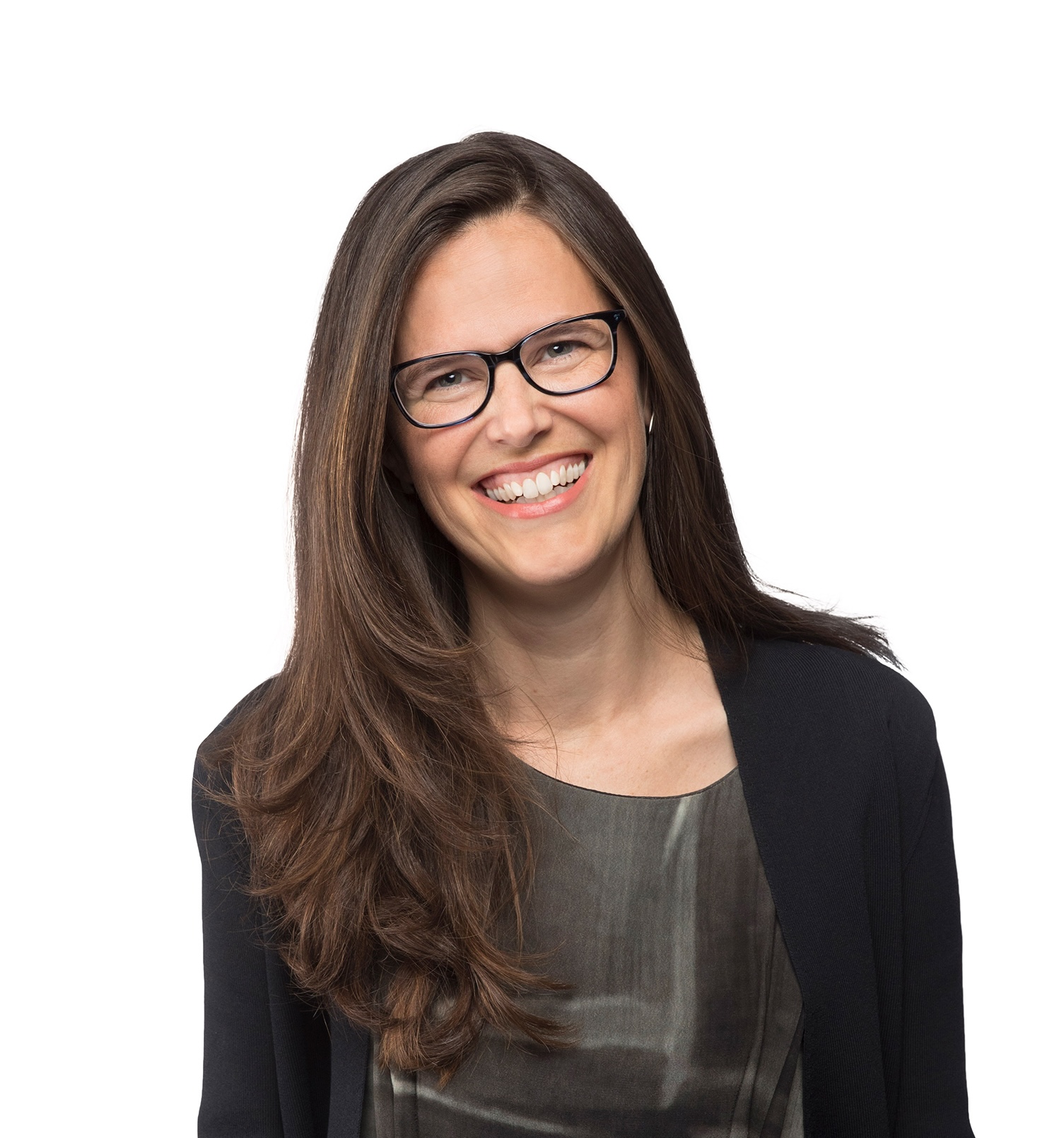 Woman with long brown hair and glasses smiles at the camera, wearing a dark jacket over a patterned top, against a white background.