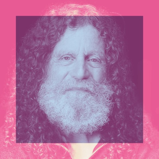 Elderly man with long curly hair and a full white beard, centered in a pink-tinted square frame with a pink background.