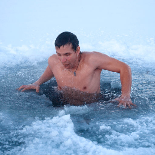 A man emerges from an ice hole in a frozen body of water, surrounded by snow and ice, taking a cold plunge during winter.