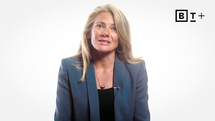 A woman with long blonde hair wearing a blue blazer and black top sits against a white background with the BT+ logo in the upper right corner.