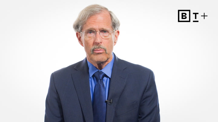 A man in a blue suit and tie sits against a plain white background with a "BT+" logo in the top right corner.